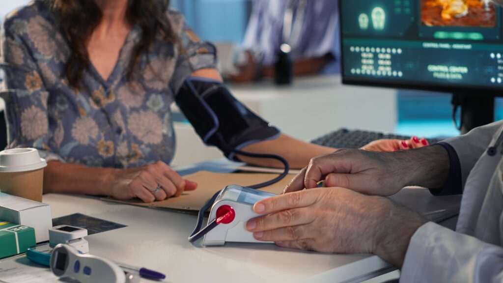 senior physician measuring blood pressure with blood pressure monitor